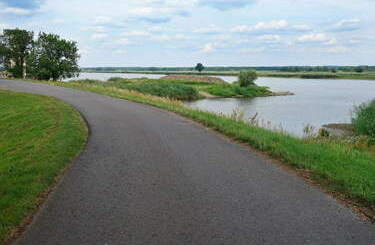 Droga asfaltowa dla pieszych wzdłuż jeziora i zielone trawniki.